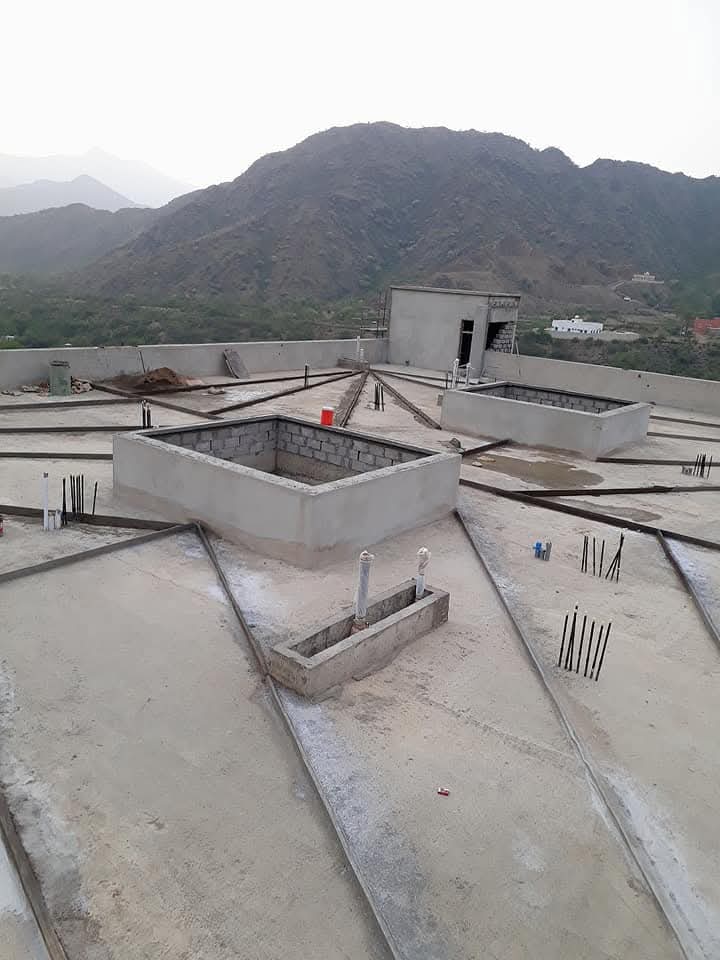 جدار من الخرسانة الرغوية قيد الإنشاء مع عمال يطبقون الطبقات بعناية